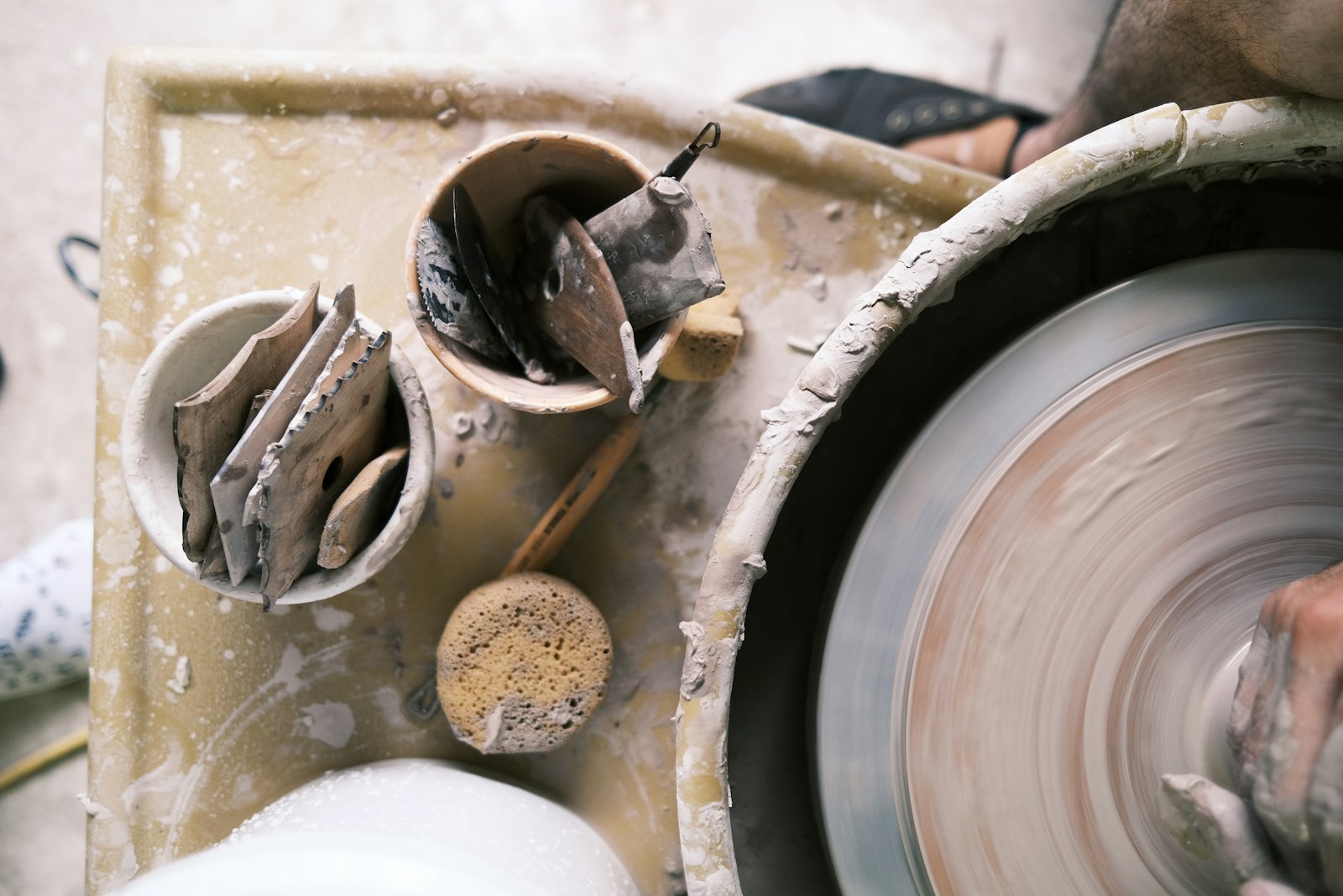 Documentary still: a potter’s wheel, tools, and wet clay in a working studio. Stock photograph — not The Clay Studio.