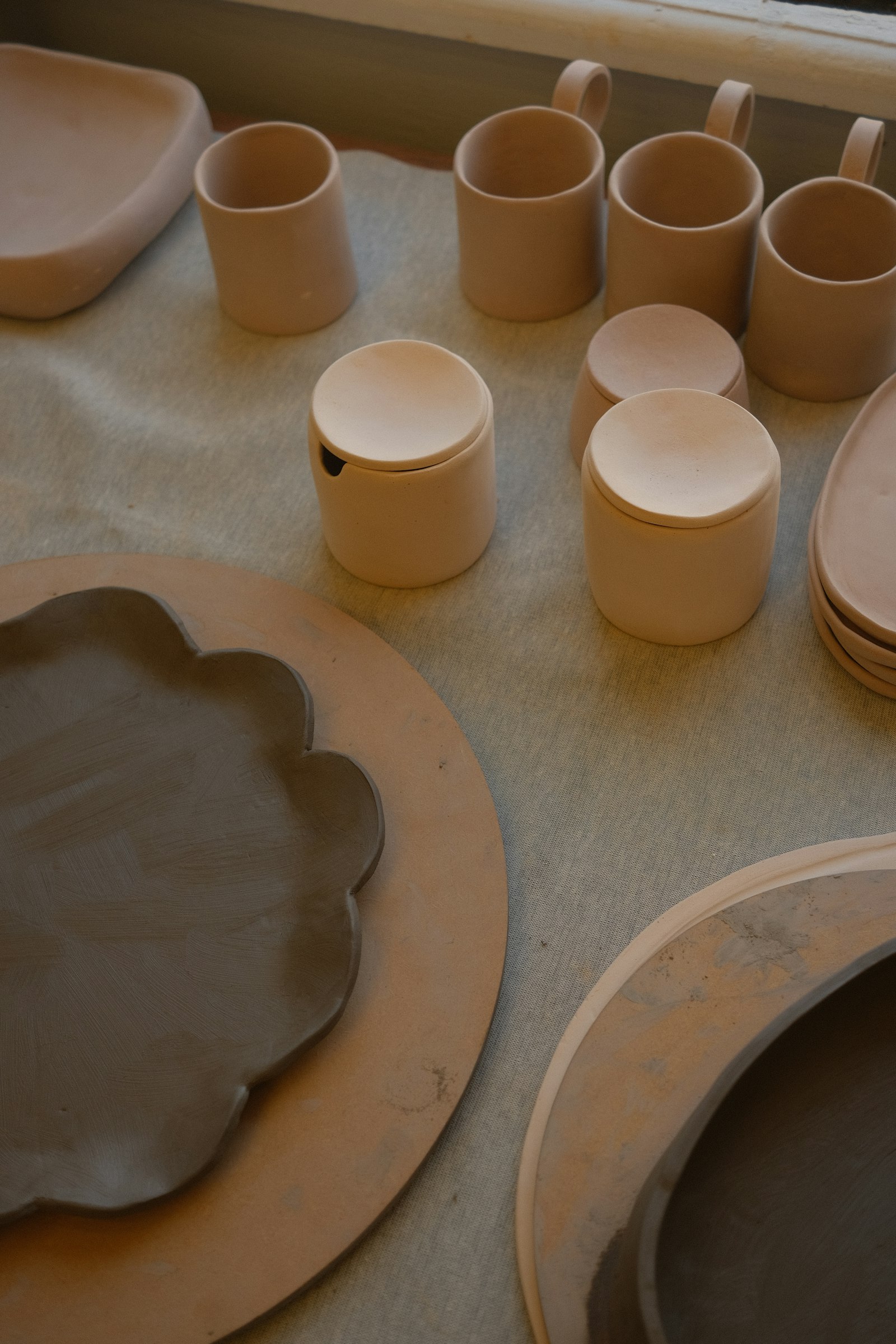 Documentary still: unfired ware and clay inventory on a studio table. Stock photograph — not Sheffield Pottery.