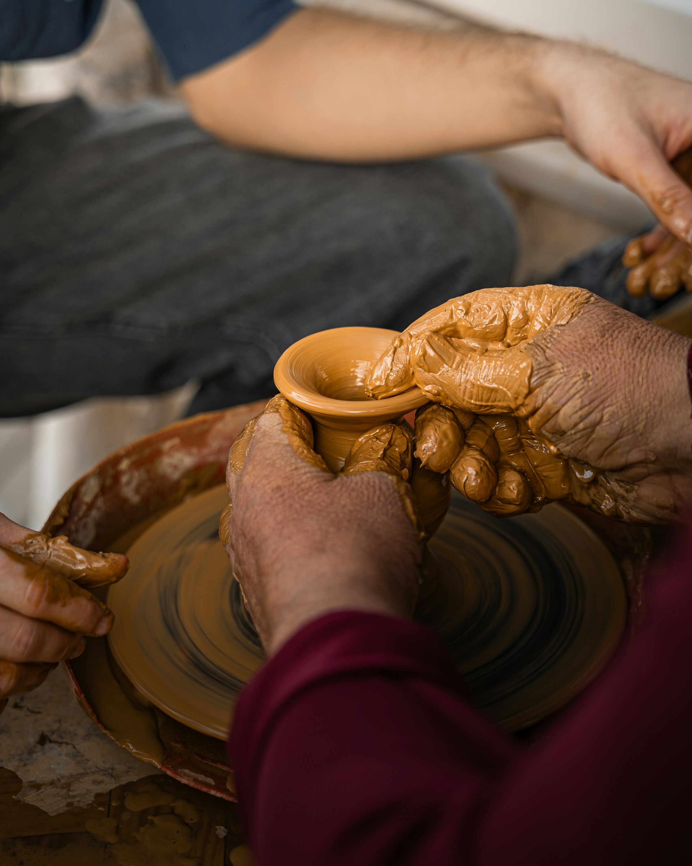 Documentary still of hands shaping wet clay on a spinning pottery wheel. Stock photograph.