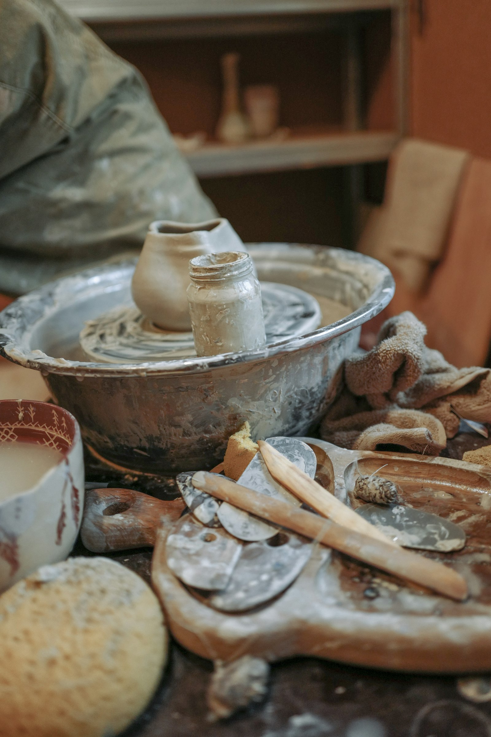 Documentary still: a potter’s wheel, tools, and wet clay in a working studio. Stock photograph — not The Clay Studio.