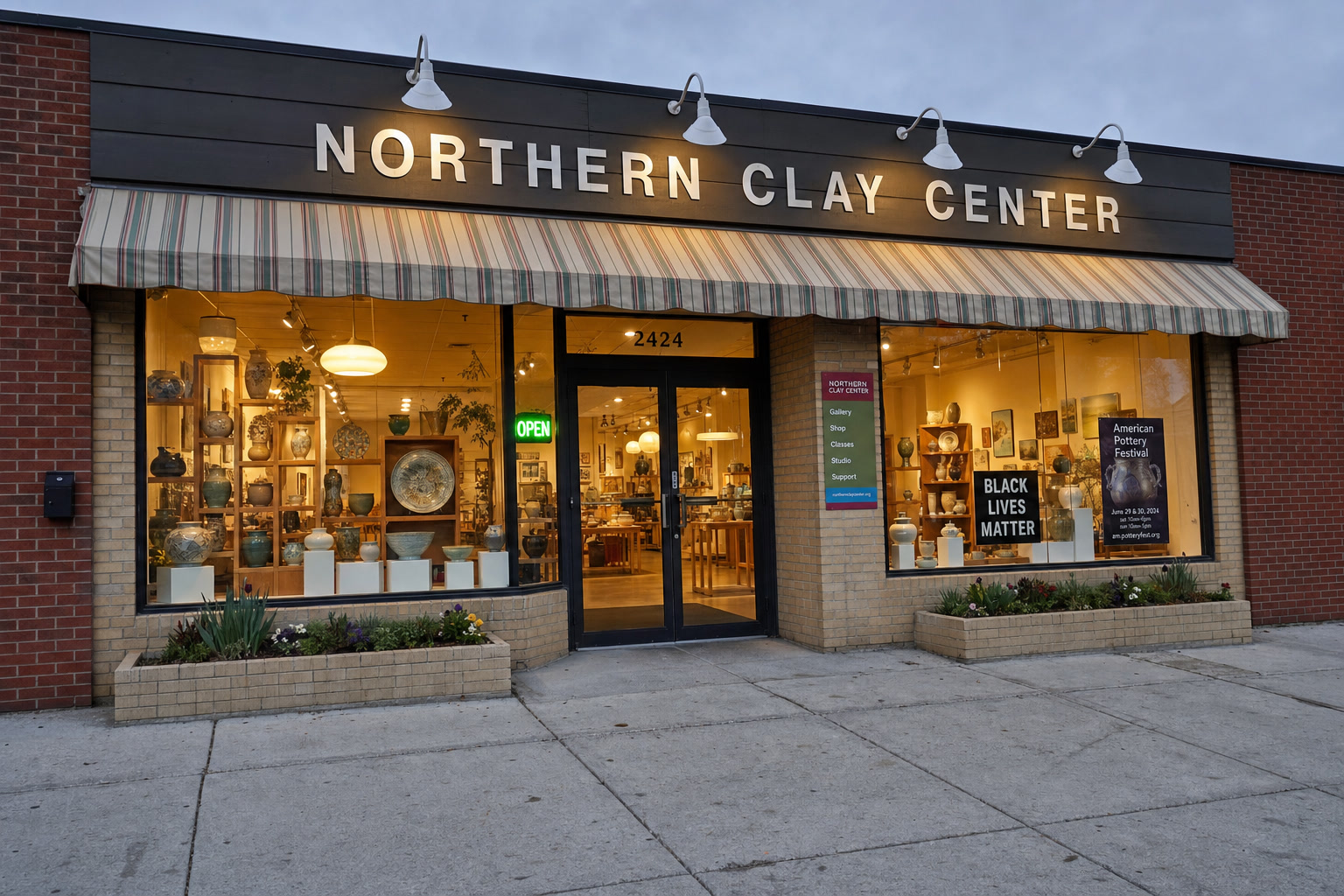 Northern Clay Center storefront at 2424 Franklin Avenue East, Minneapolis, MN. Evening, NORTHERN CLAY CENTER sign, galleries visible through the windows.